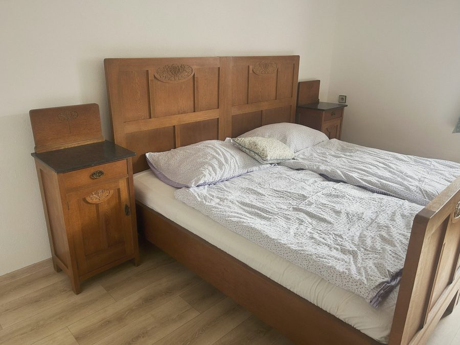 Manželská postel s vyřezávaným čelem a noční stolky