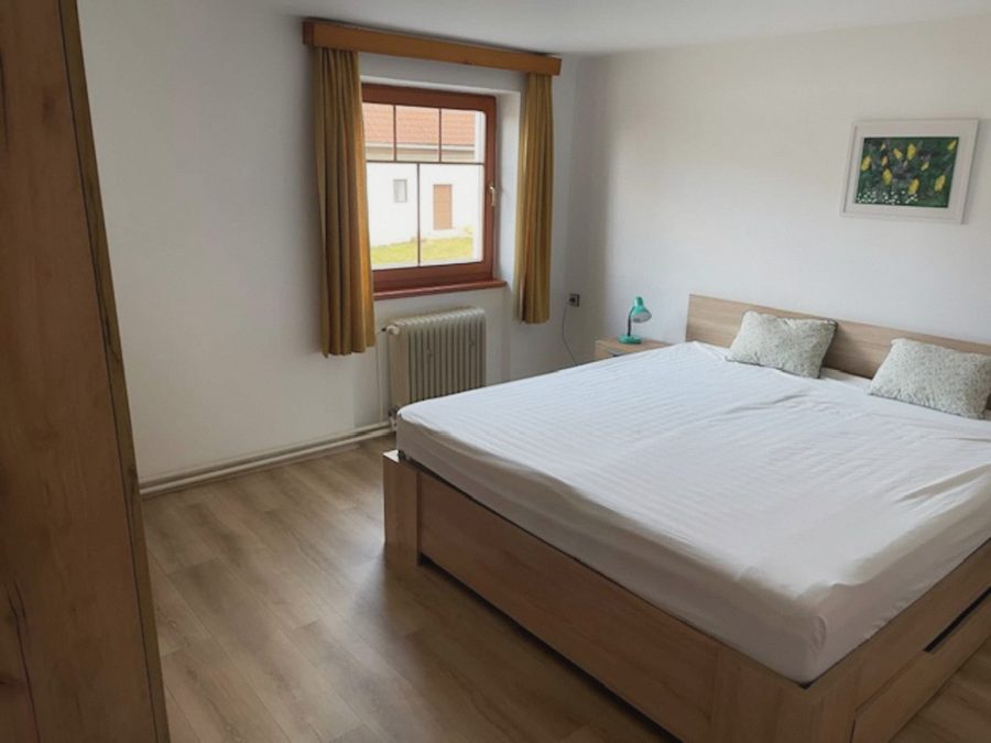 Světlá ložnice s manželskou postelí a oknem